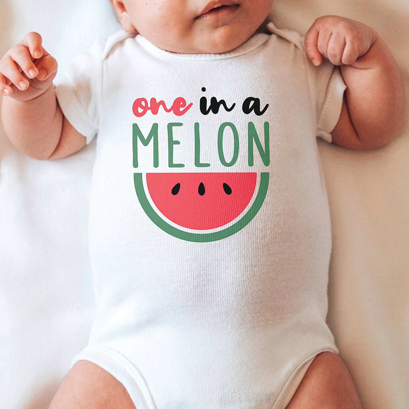 little baby wearing white onesie with pink black and green one in a melon watermelon print