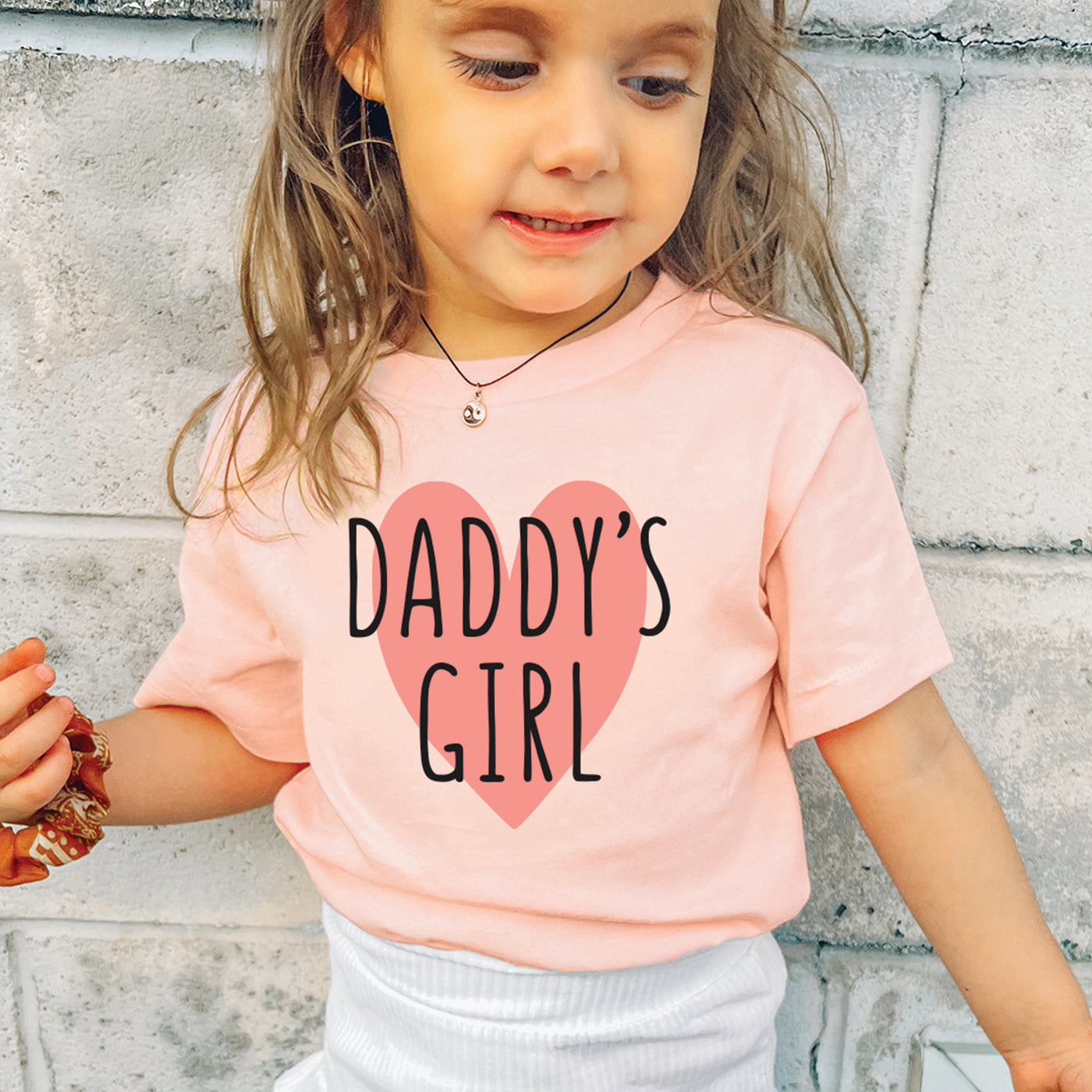 cute little girl wearing heather peach tshirt with pink and black DADDY'S GIRL print inside big heart print