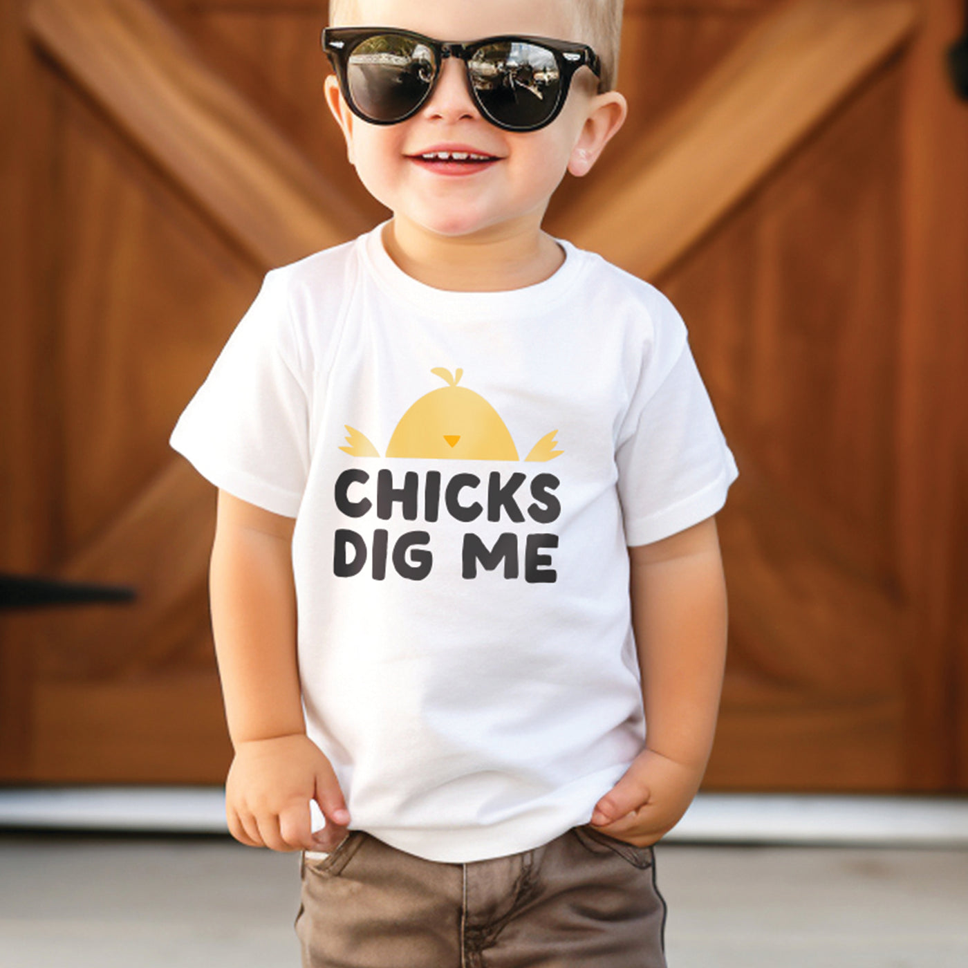 Little boy wearing white shirt with yellow orange and black CHICKS DIG ME baby chicken print