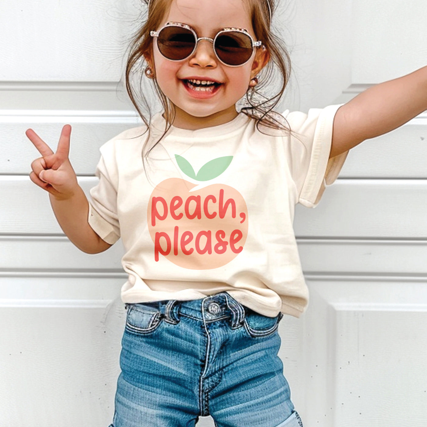 Coral pink and tan "happy camper" mountain, moon and arrow design on white gender neutral toddler crew neck tee.